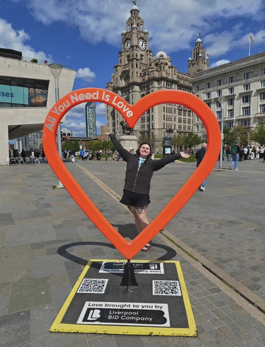 Jessica Condon standing inside a red love heart sculpture in Liverpool